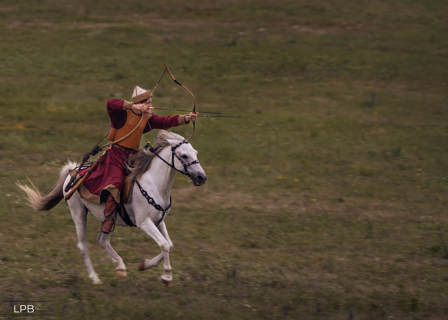 A lone horse-archer at full gallop through a wildflower field